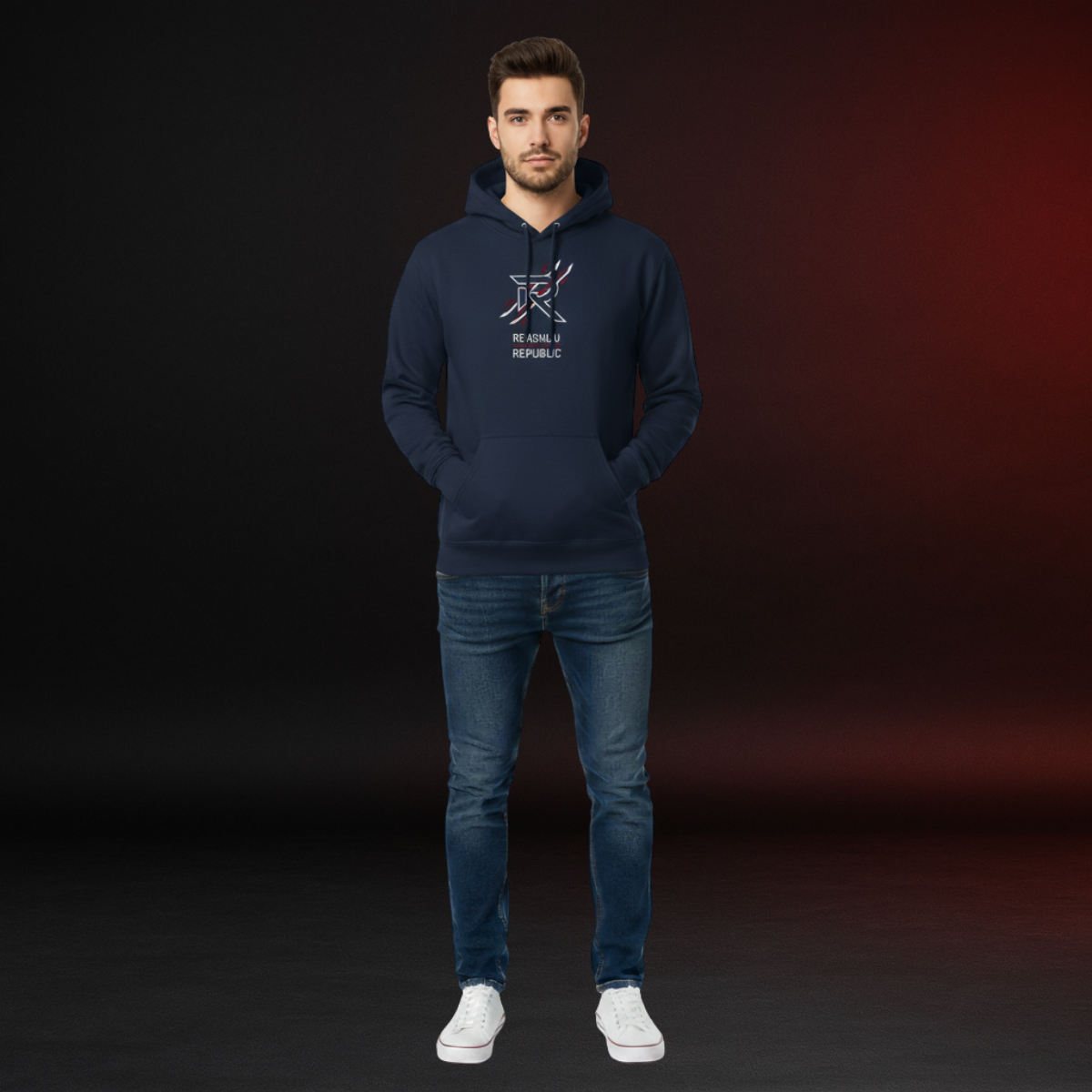 Man wearing a navy hoodie with a logo and text, standing against a dark background