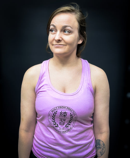 Woman wearing a purple tank top with a logo and text on a dark background