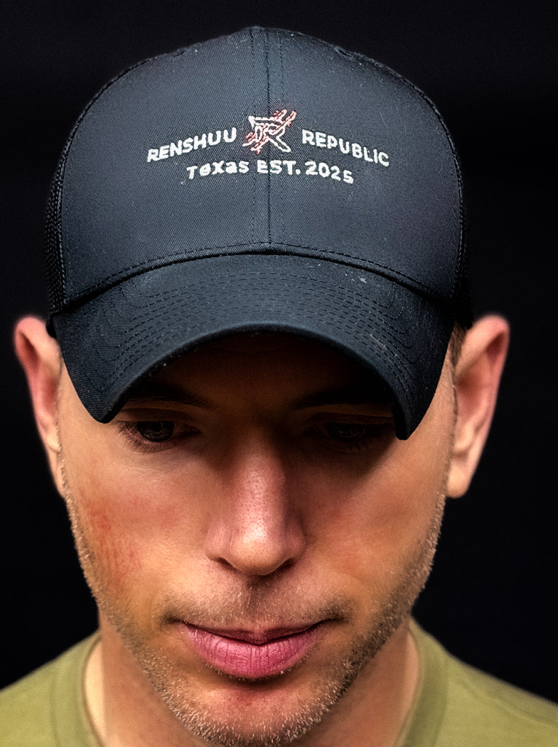 Man wearing a navy blue cap with text and logo on a black background
