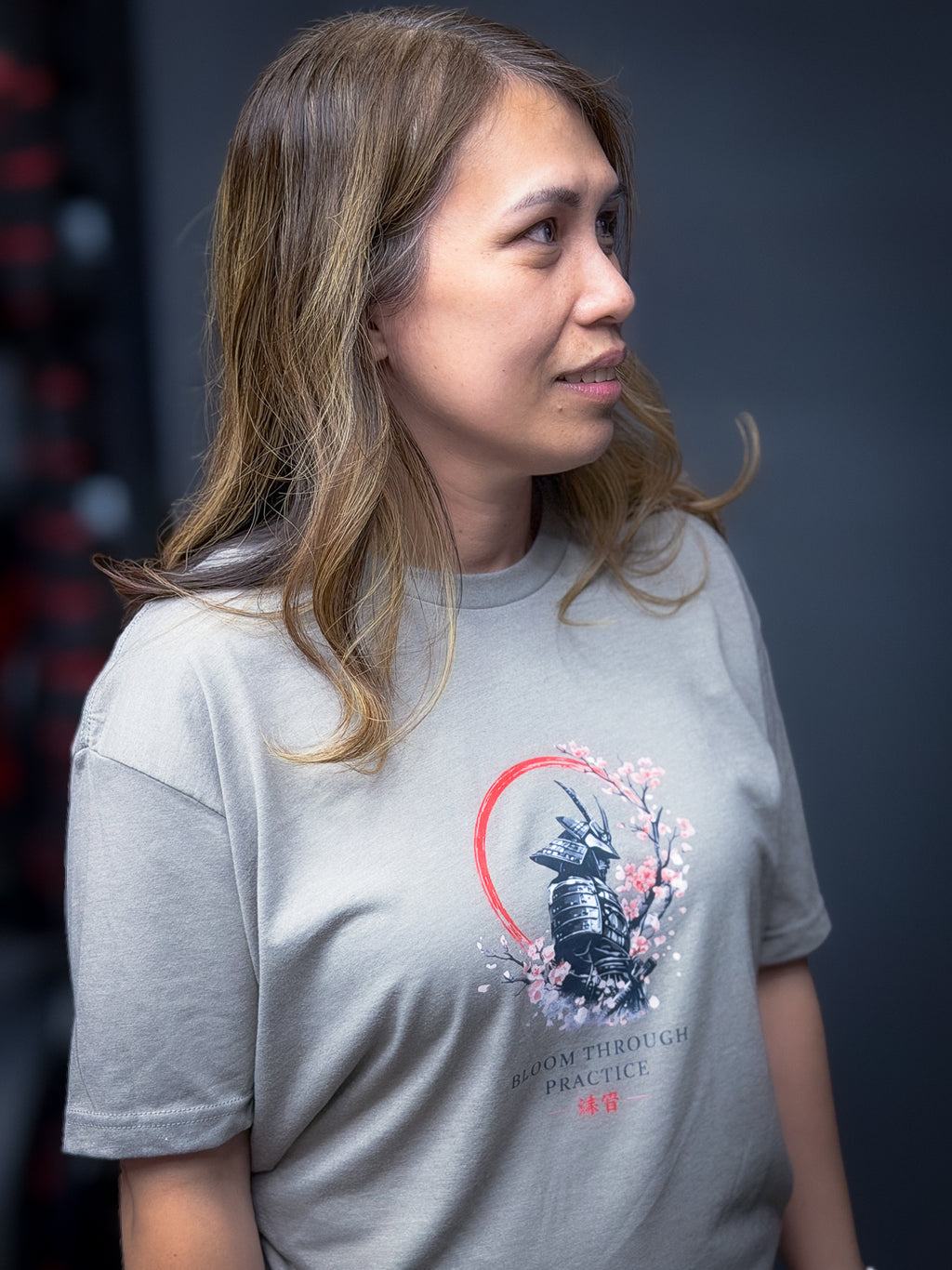 Woman wearing a gray t-shirt with a graphic design on a dark background