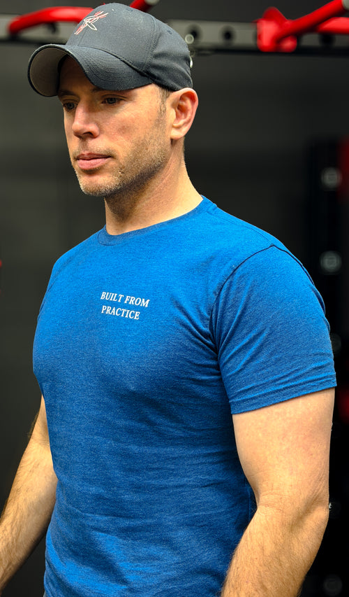 Man wearing a blue t-shirt with text and a cap, standing against a blurred background.