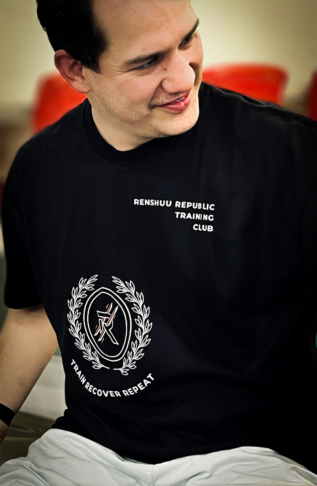 Man wearing a black t-shirt with text and logo