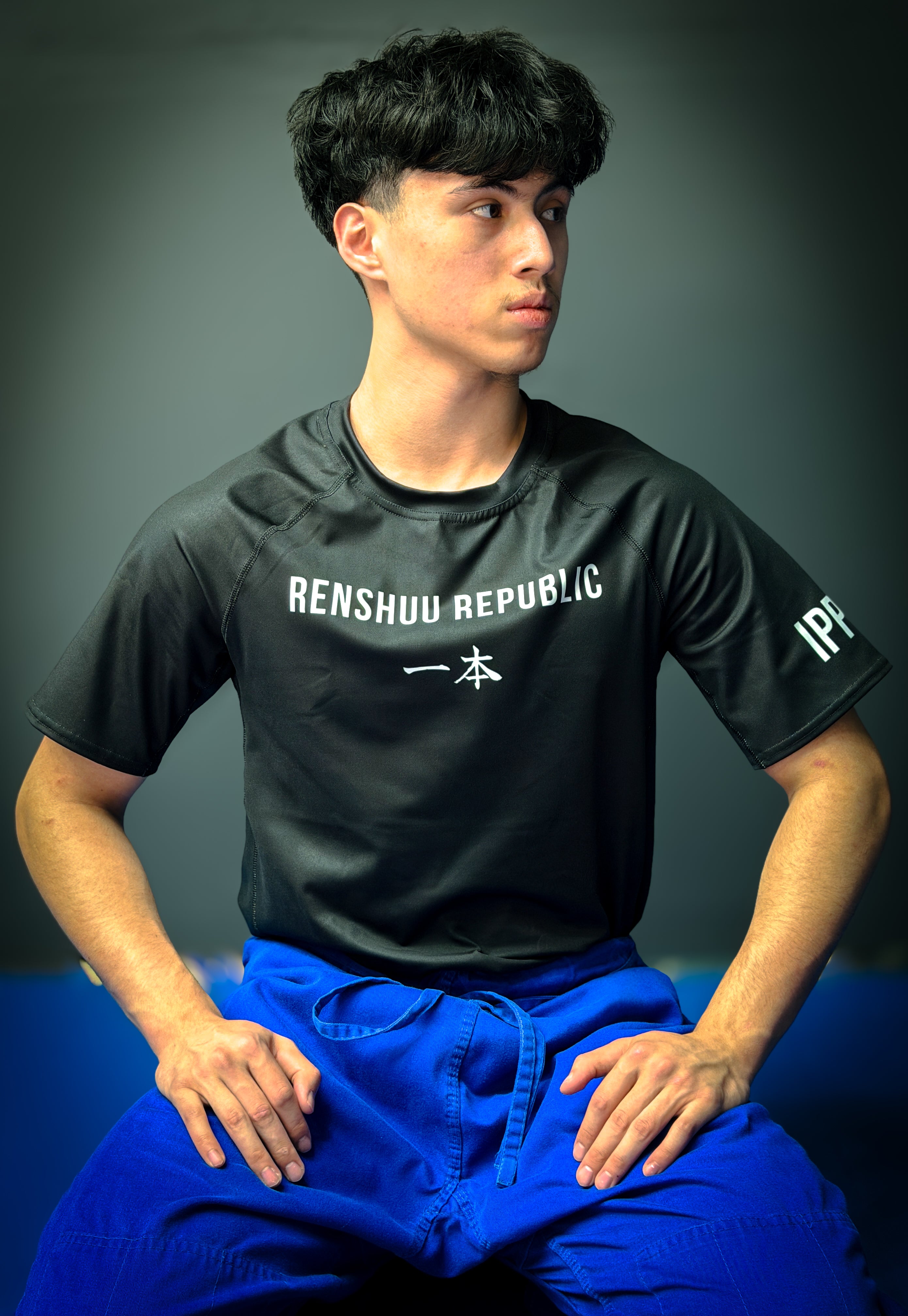 Person wearing a black 'RENSHUU REPUBLIC' t-shirt with blue pants against a dark background
