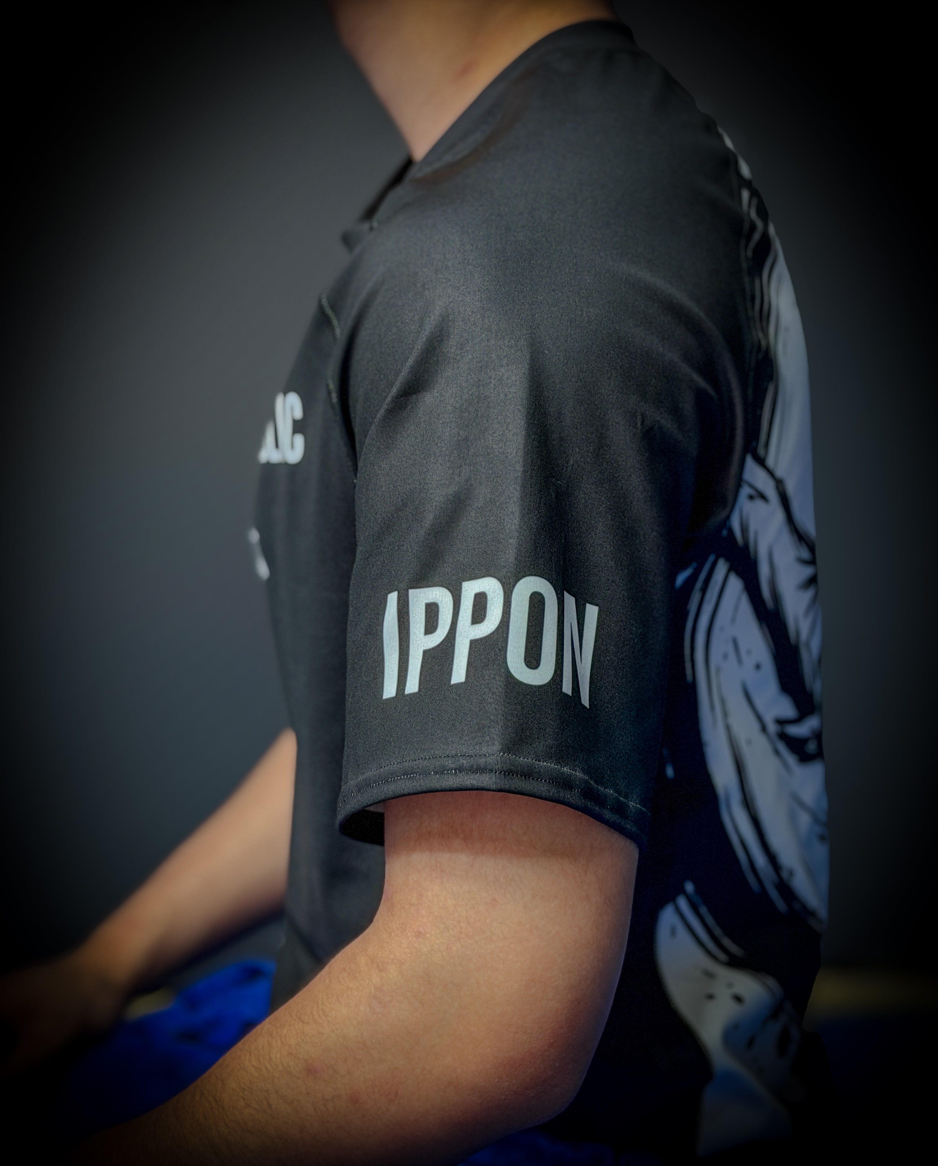 Person wearing a dark gray t-shirt with 'IPPON' printed on it, standing against a dark background.
