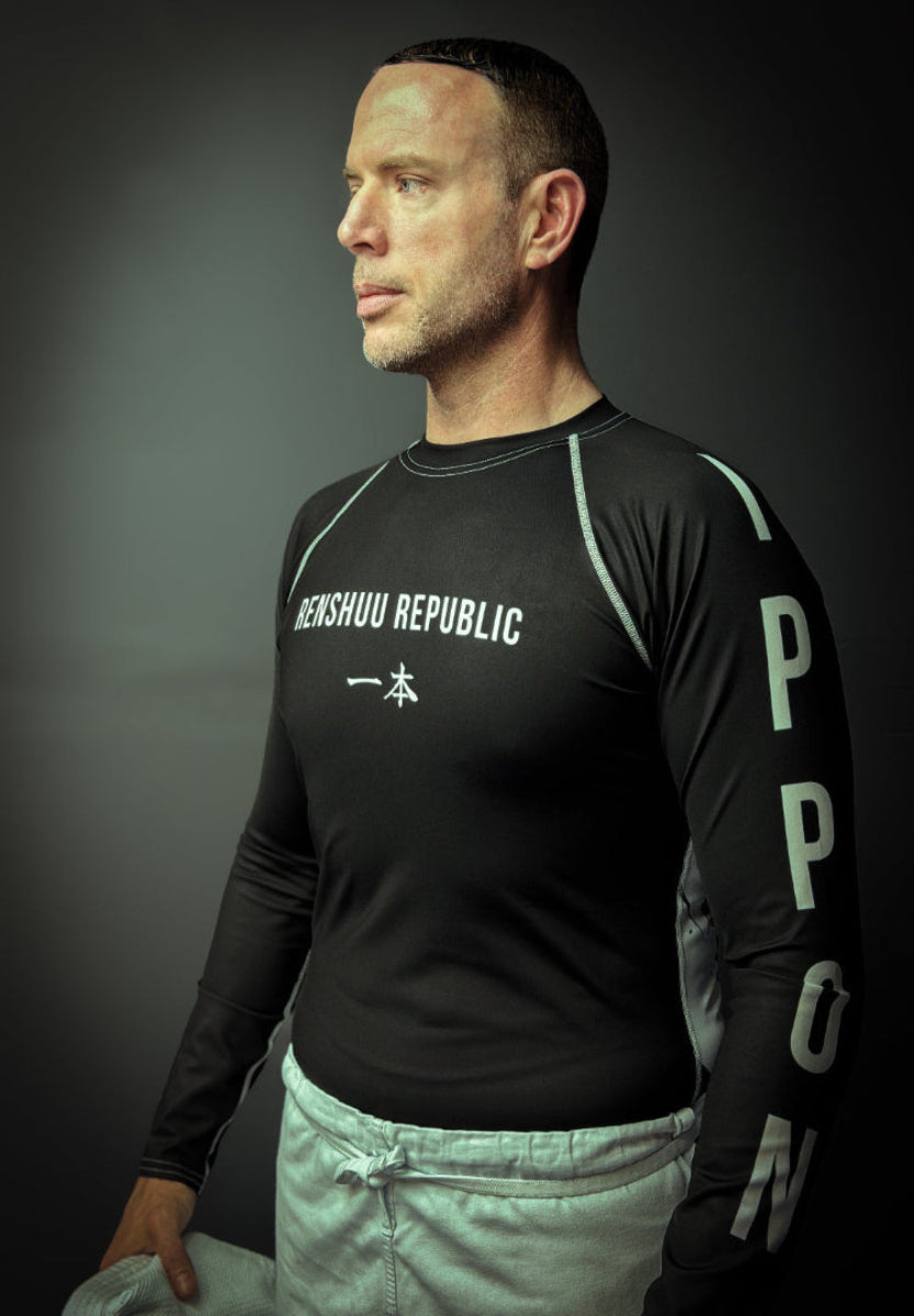 Man wearing a black athletic shirt with visible branding against a dark background