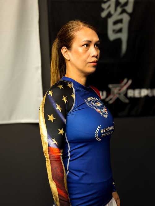 Woman wearing a blue athletic outfit with star design, standing in front of a blurred background with text.