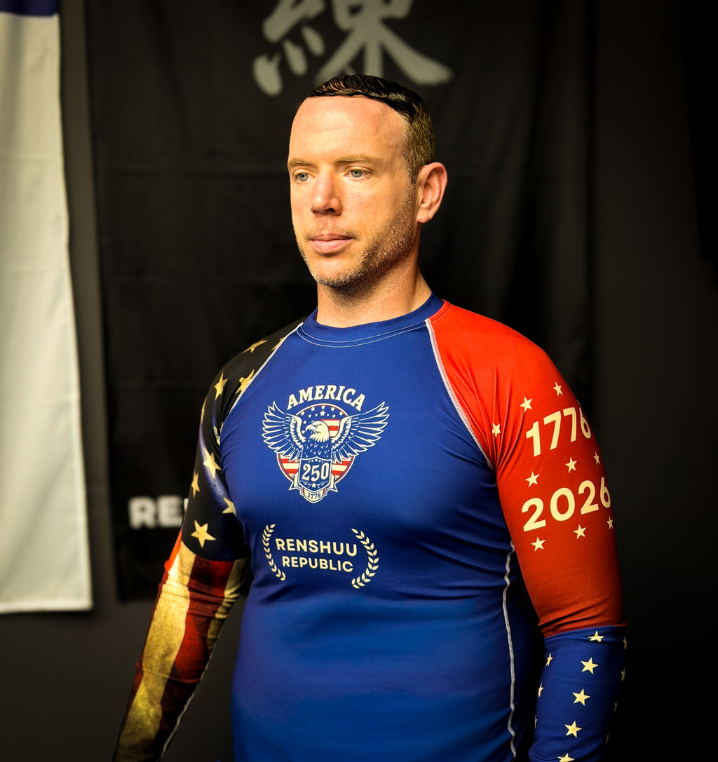 Man wearing a blue and red long-sleeve shirt with patriotic design in front of a black background.