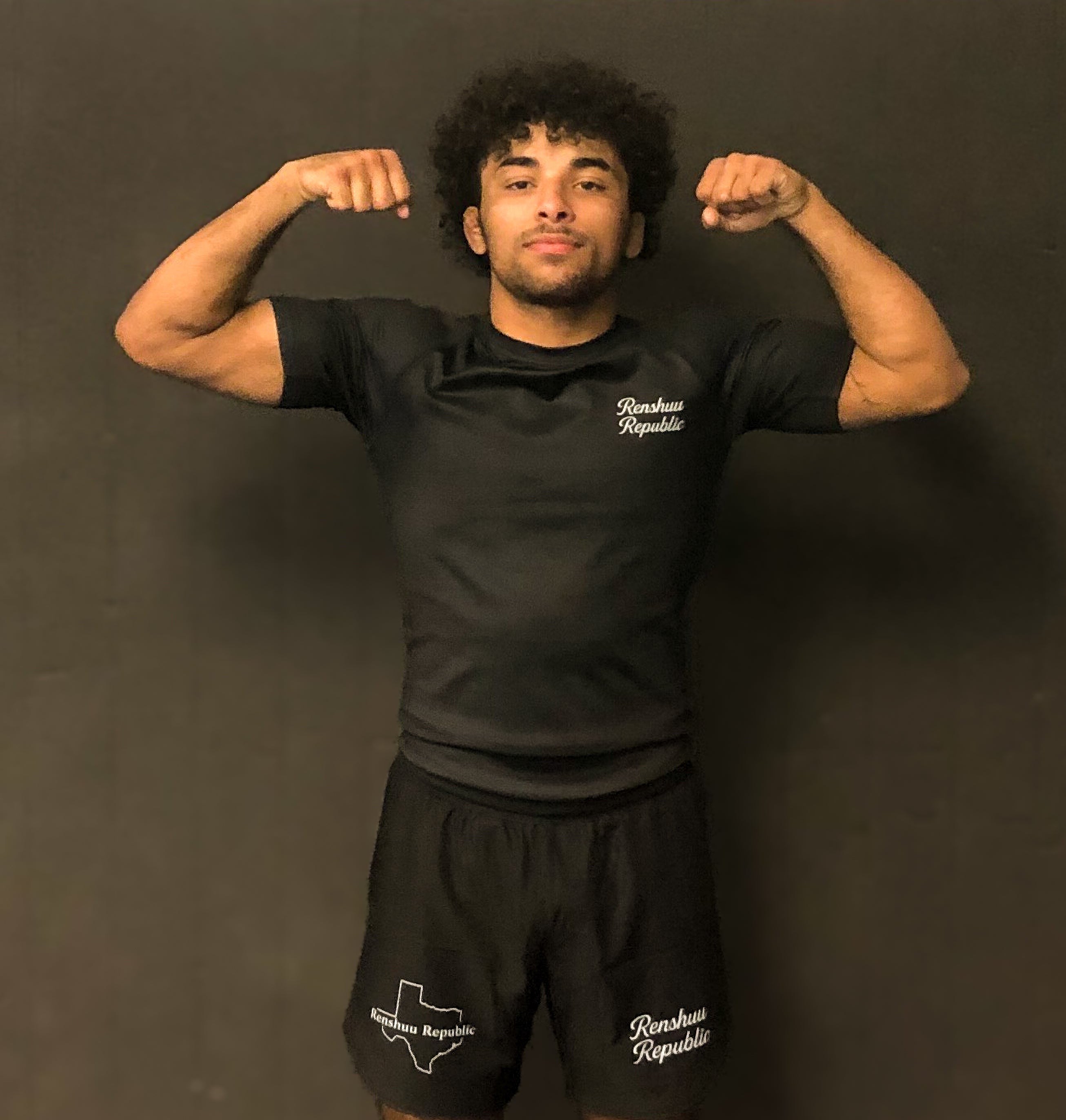 Person wearing black athletic wear with visible branding against a dark background