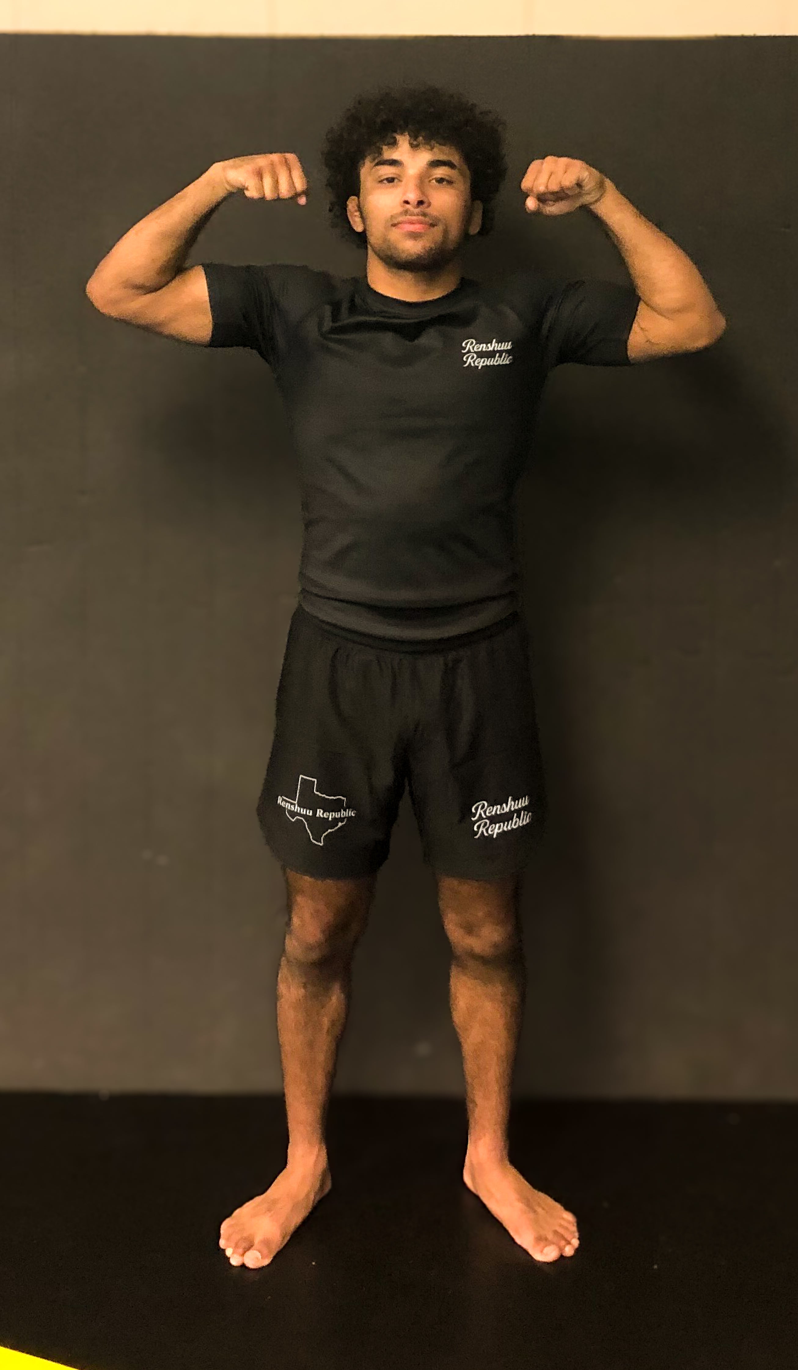 Person wearing black athletic wear with branding against a dark background