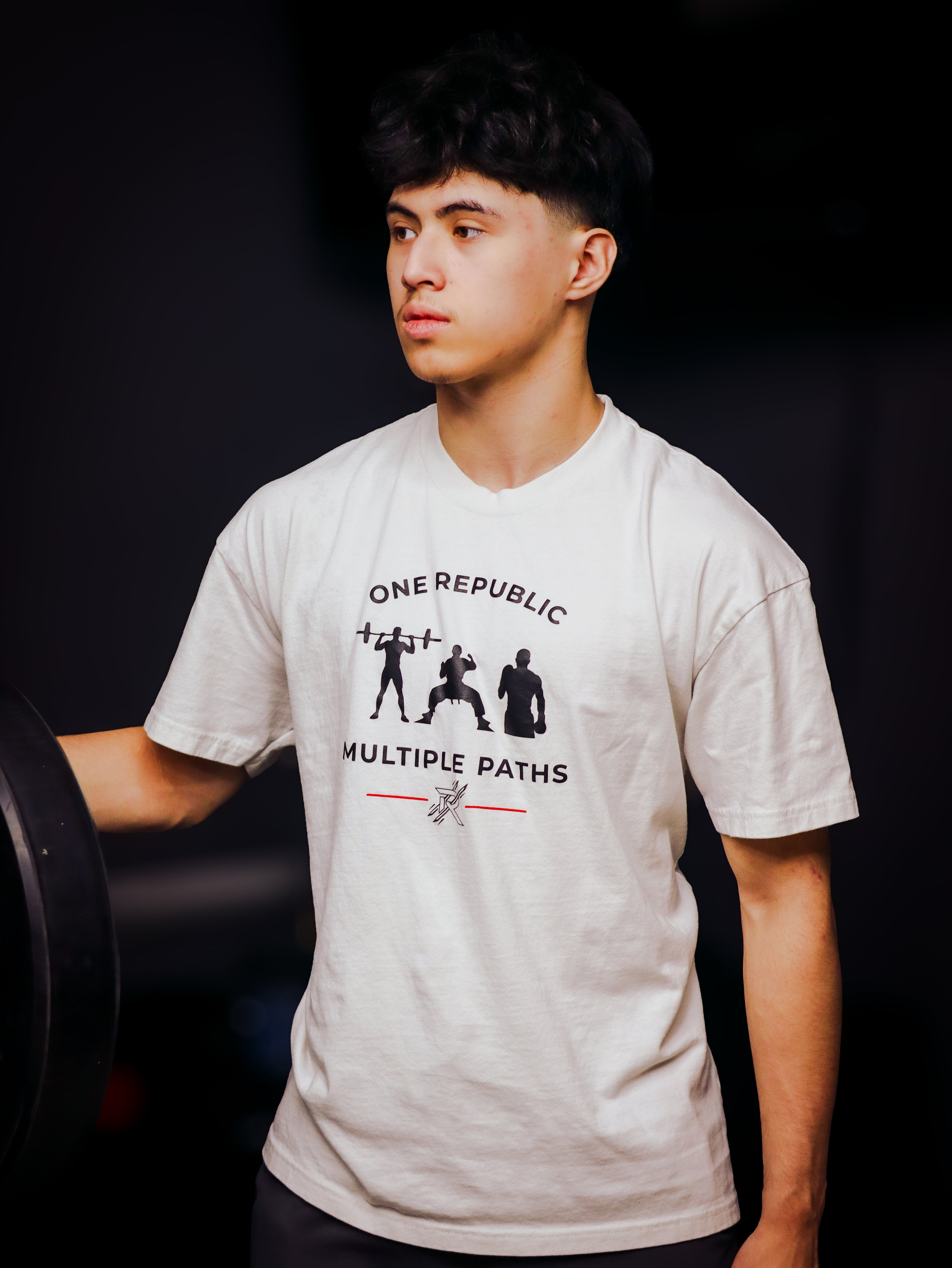 Person wearing a white t-shirt with a graphic design on a black background