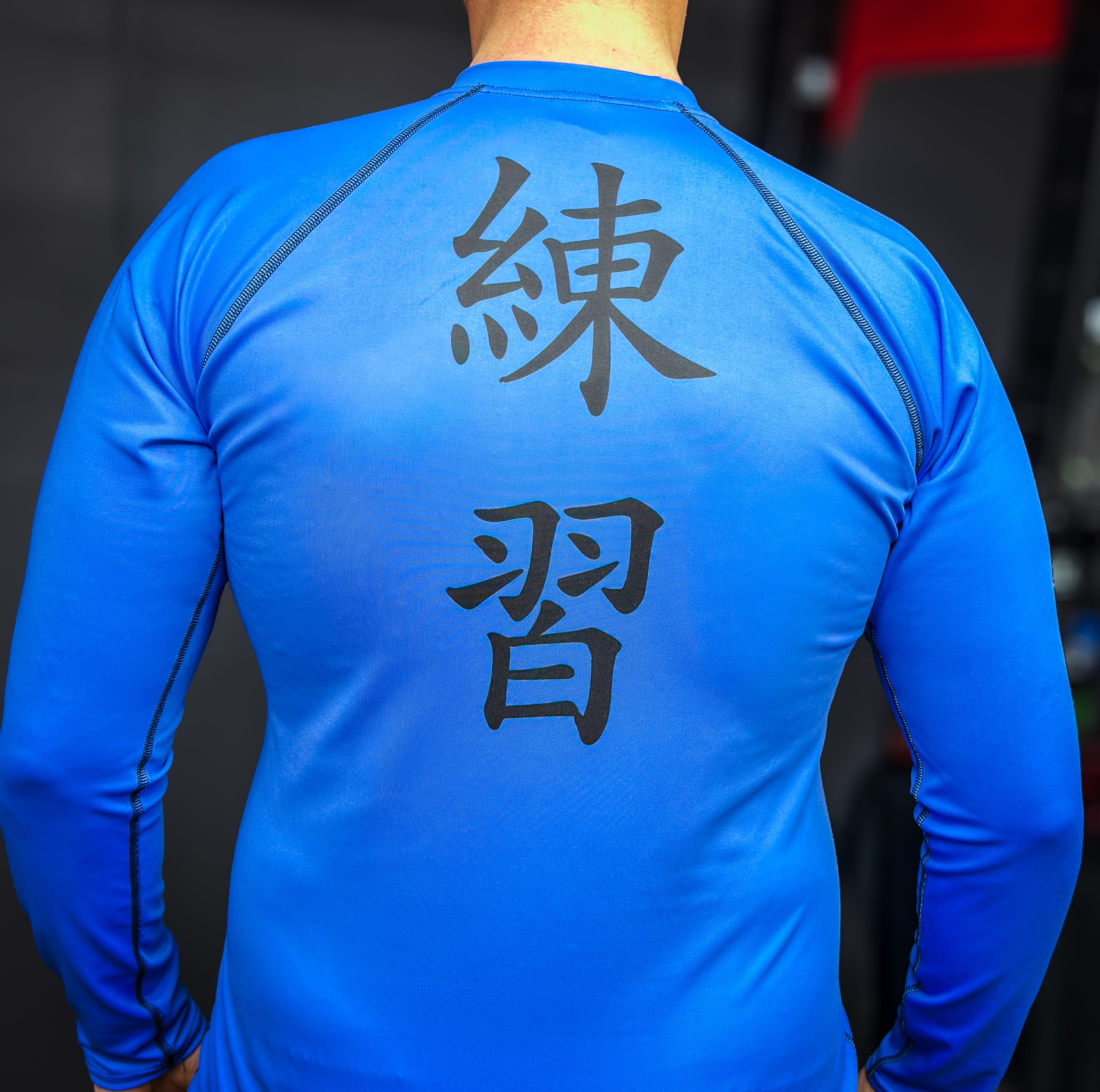 Blue athletic shirt with black text on the back, worn by a person.