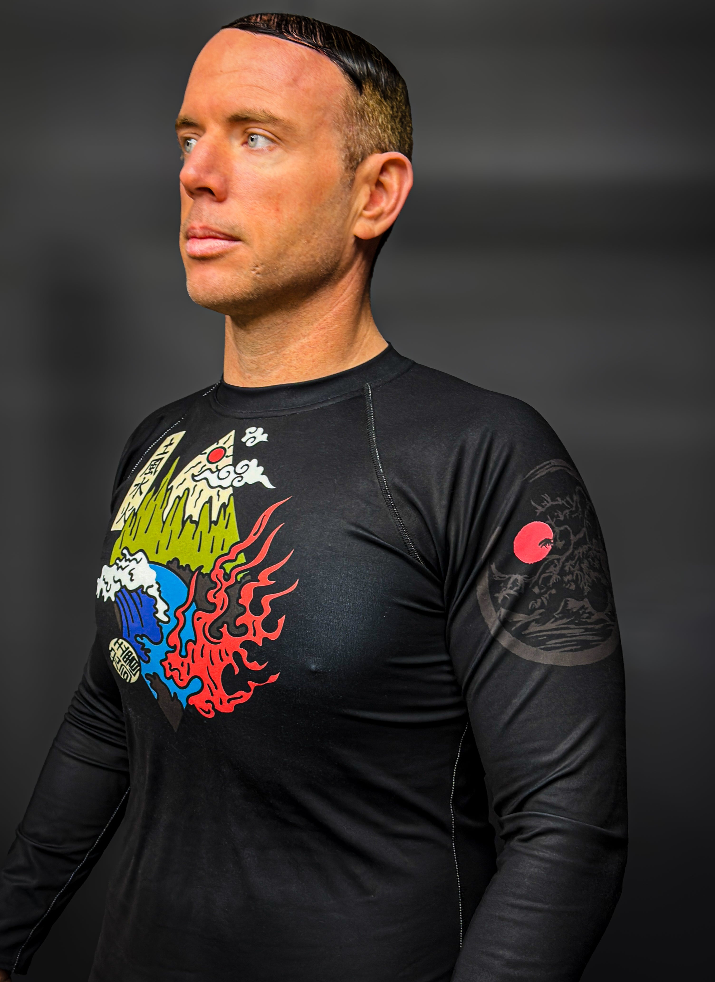 Man wearing a black long-sleeve shirt with colorful graphics on a dark background
