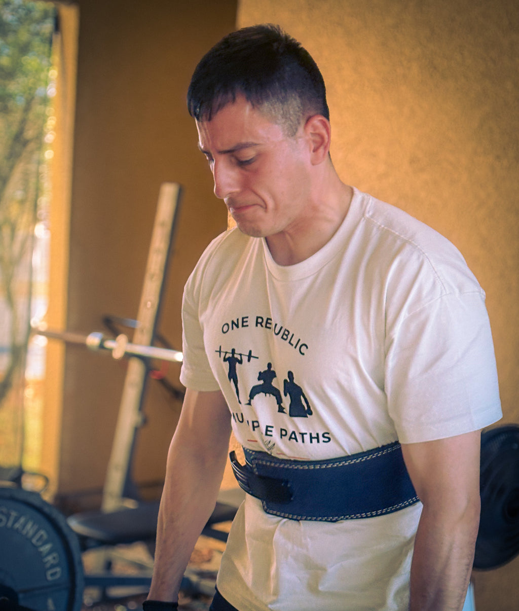 Man wearing a white t-shirt with 'One Republic' logo in a gym setting