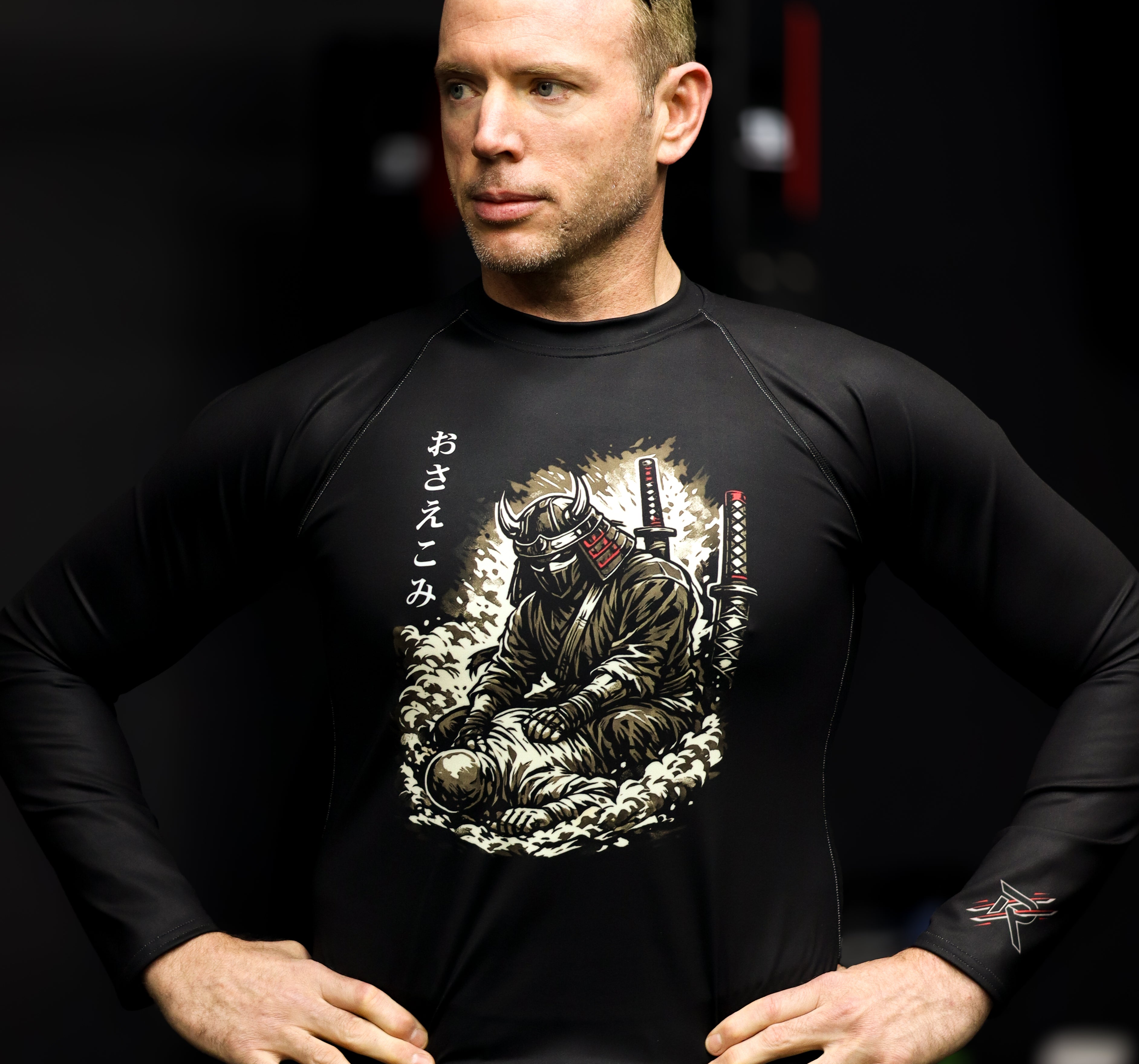 Man wearing a black long-sleeve shirt with a graphic design on a dark background